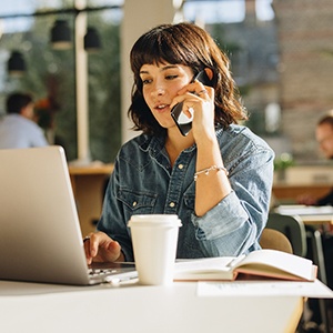 Woman talking on phone and looking at laptop
