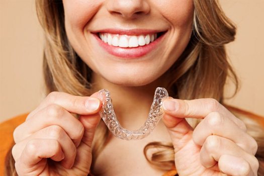 a woman holding an Invisalign tray
