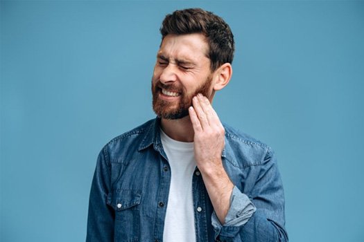 a man touching his jaw due to tooth pain