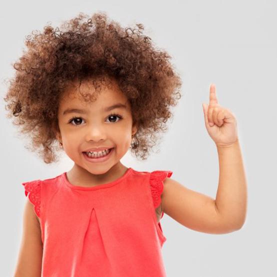 Child smiling and pointing her finger upwards
