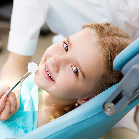 A girl smiling in the treatment chair in preparation for dental sealants