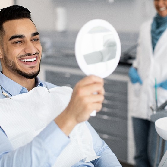 Dentist holding shade guide to woman’s teeth