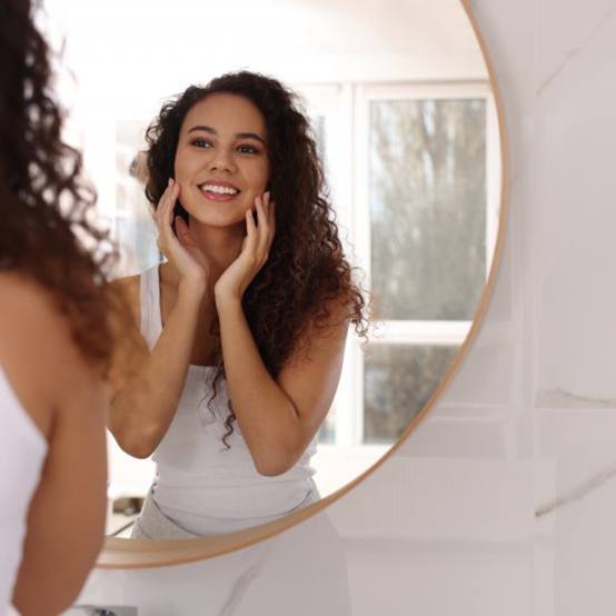 Woman smiling in her bathroom mirror