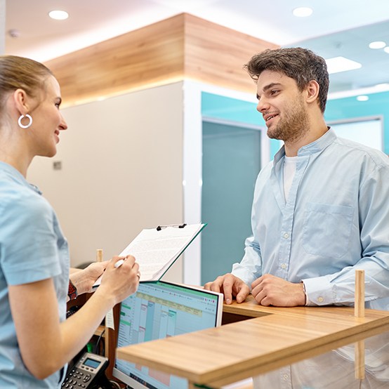 a man speaking with a front desk staff member at a dental office