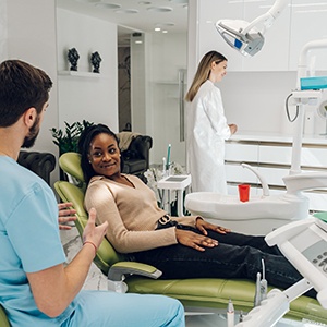a patient sitting in a dental chair talking to a dentist