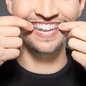 a man putting a whitening strip over his teeth