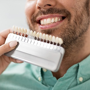 a dentist putting a shade chart up to a patient’s teeth