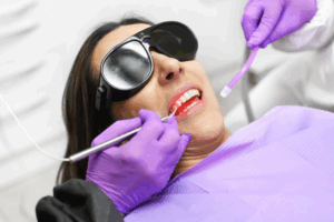 Patient smiling while dentist whitens her teeth in-office
