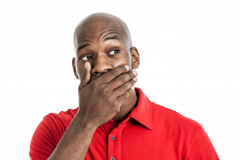 Patient holding mouth in surprise after getting discount dental implants